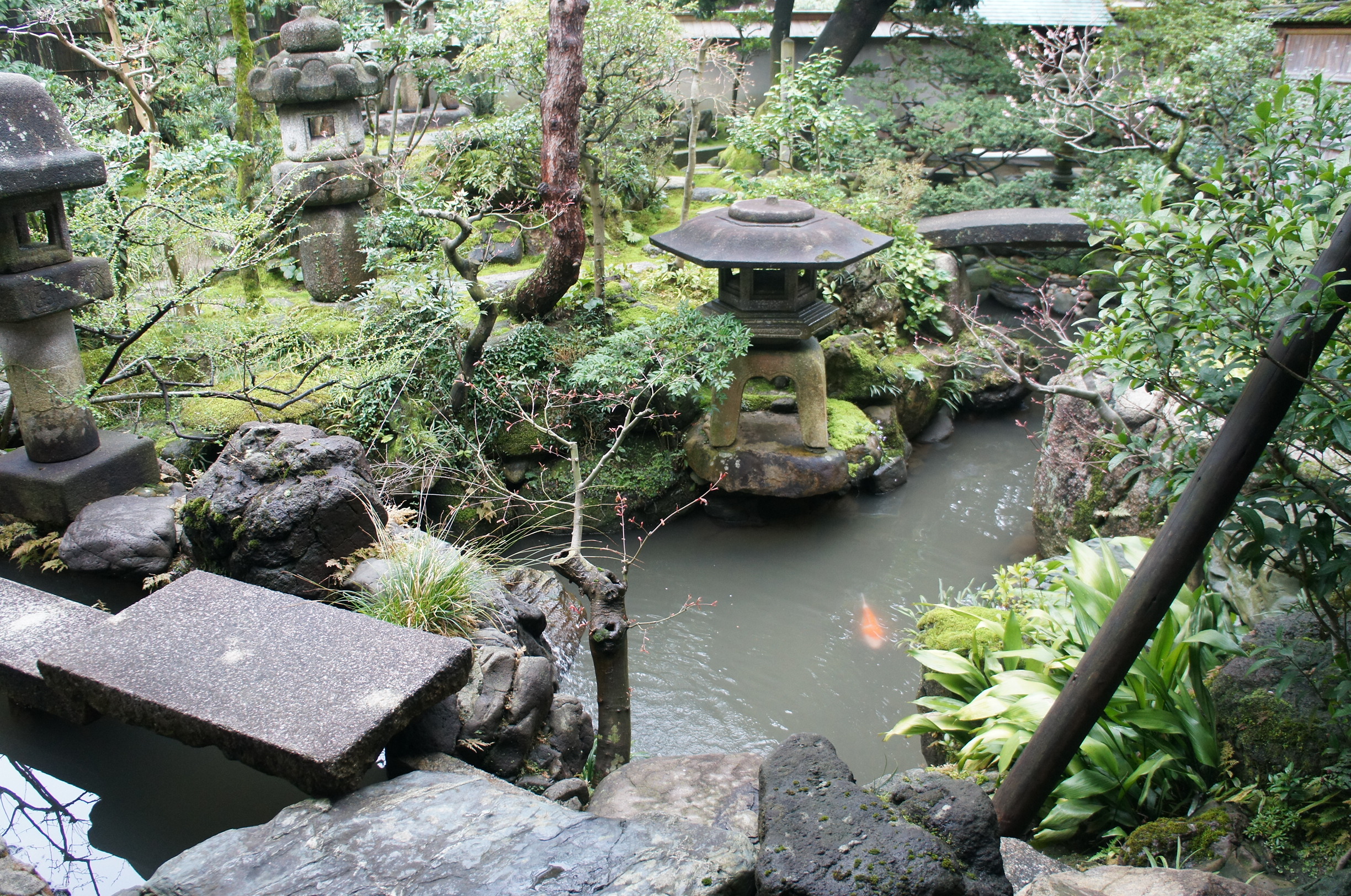 Inner garden with stone lanterns, waterfall, and a pond of colorful koi carp.