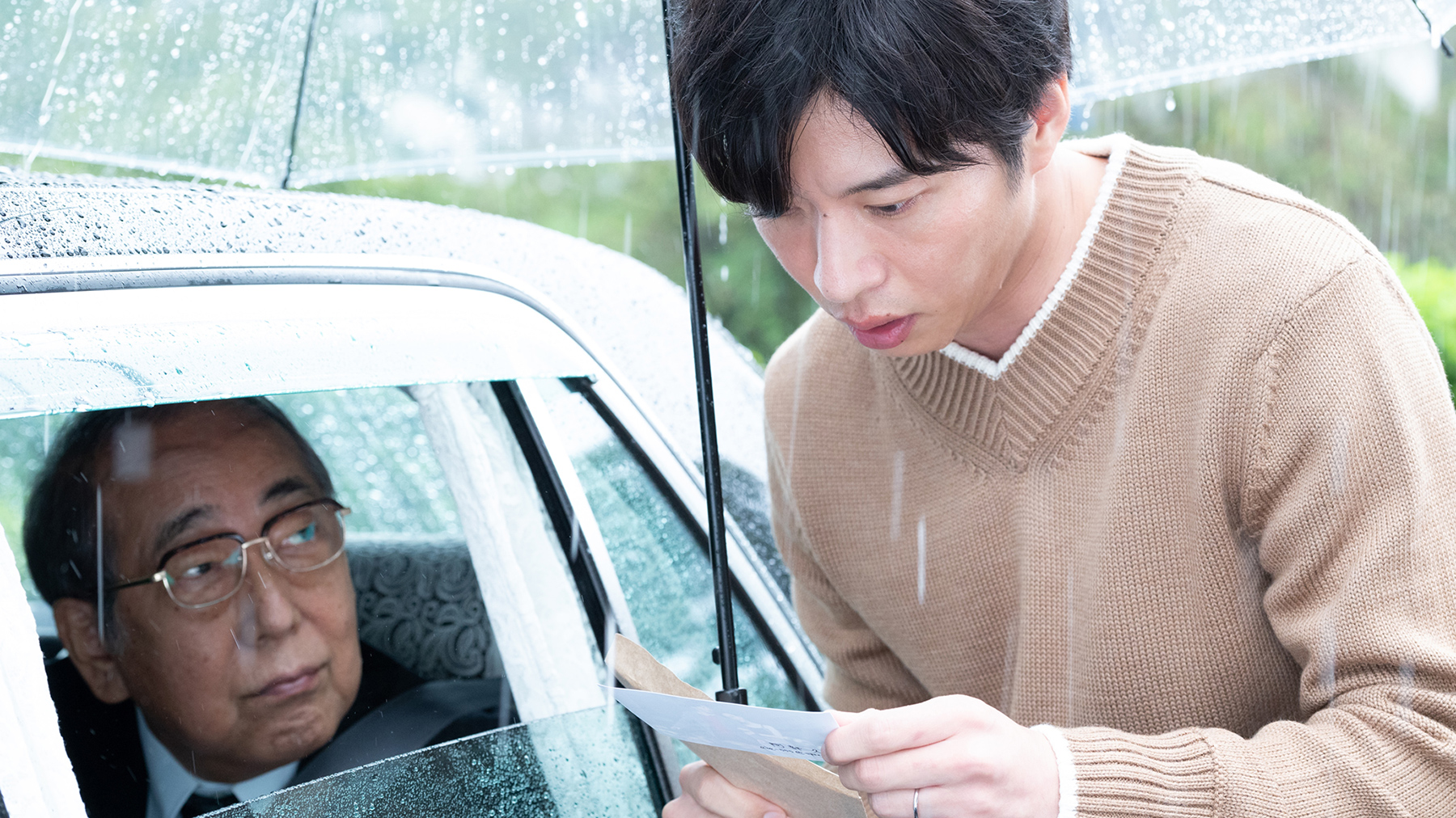 man standing outside of car in the rain