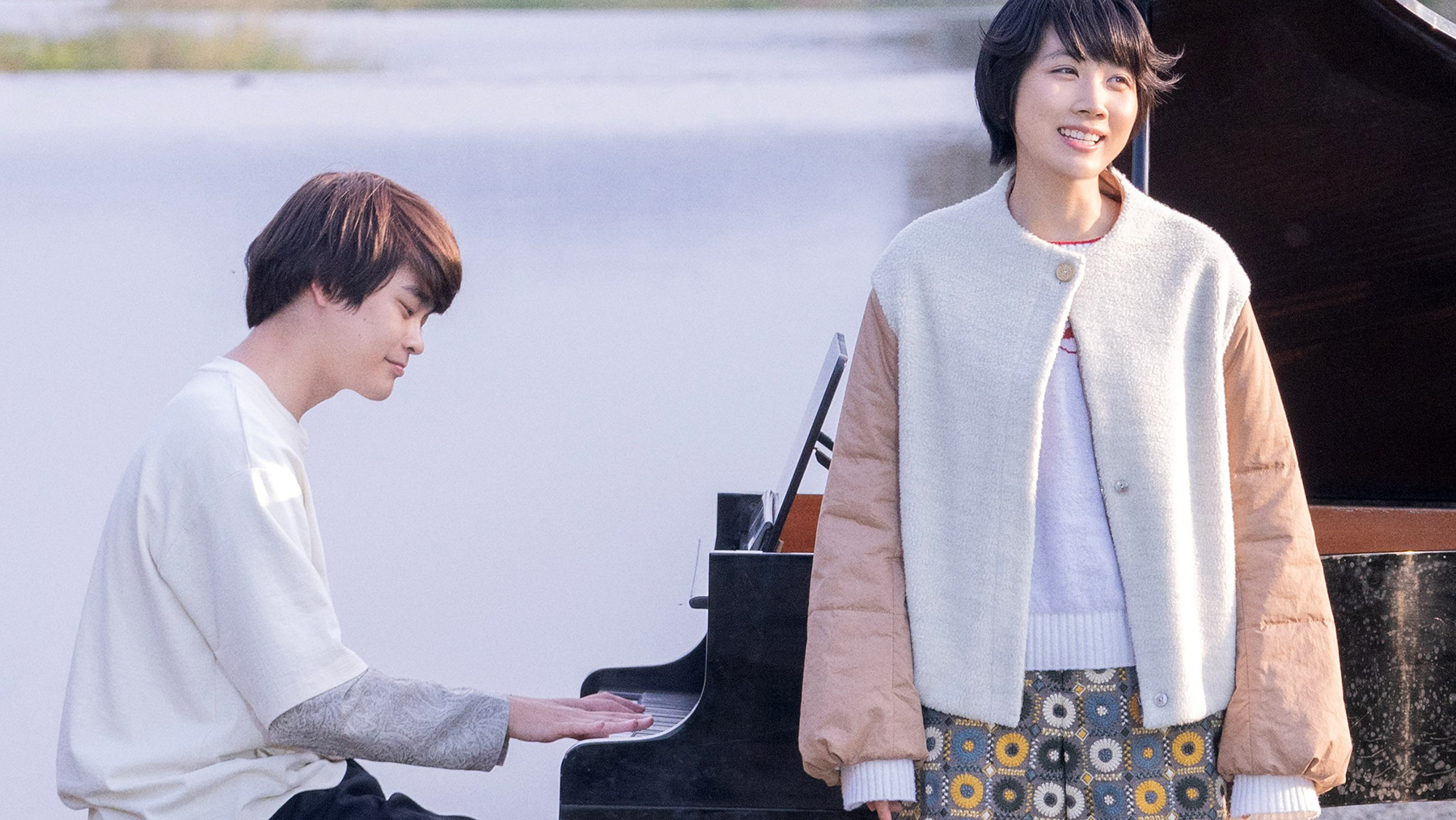 man playing piano with woman in front
